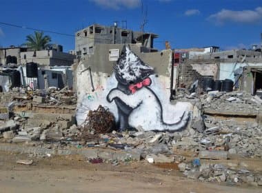 Artista de identidade desconhecida, Banksy grafita em escombros na Faixa de Gaza
