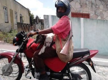  Homem desfila com cães e espingarda sobre moto na Bahia